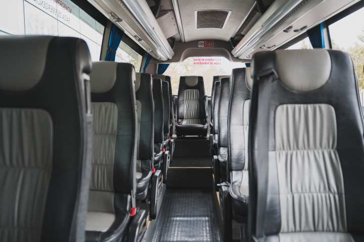 Interior of an empty bus with rows of black and gray seats.