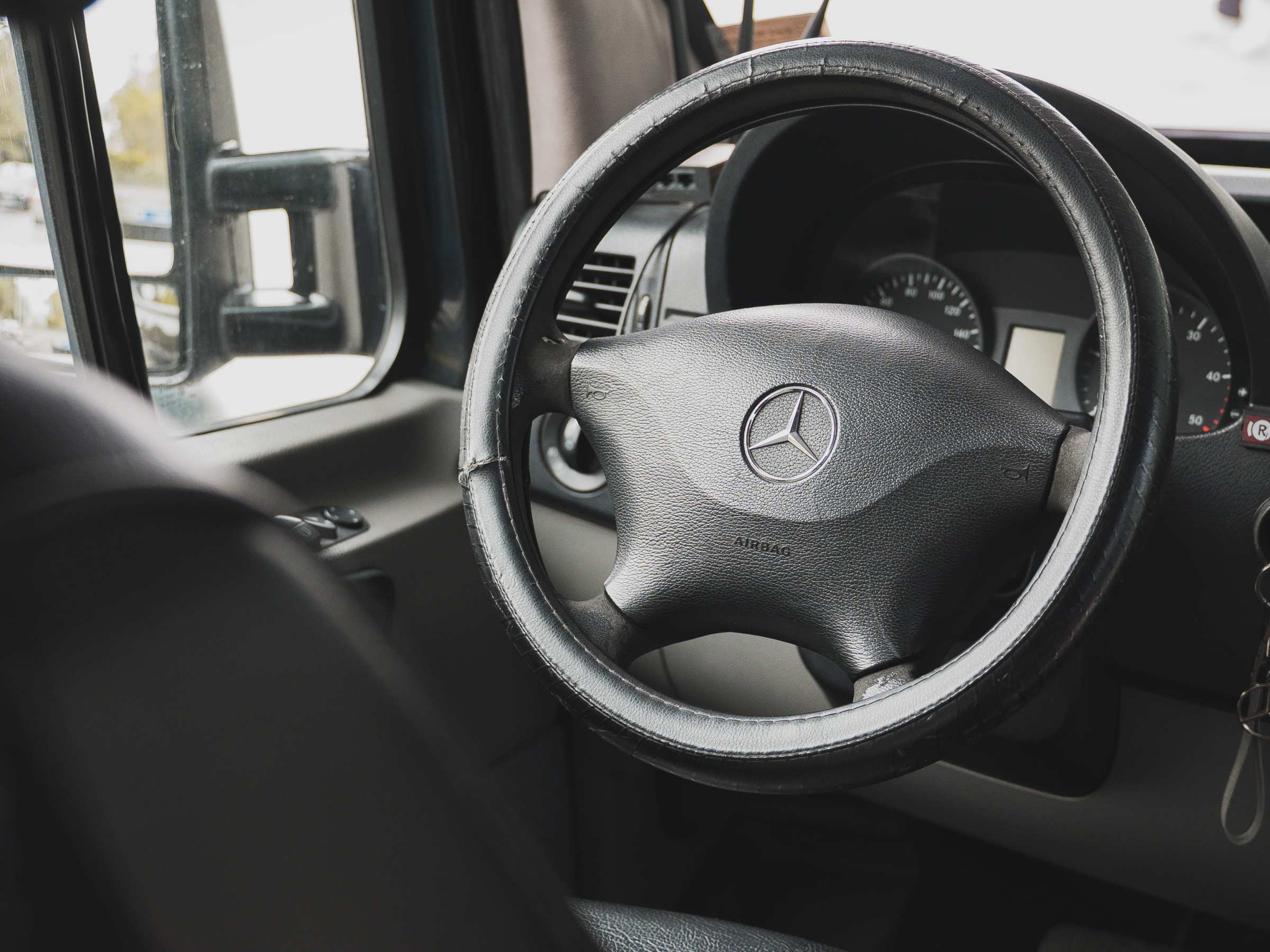 Close-up of a Mercedes-Benz steering wheel and dashboard inside a vehicle.