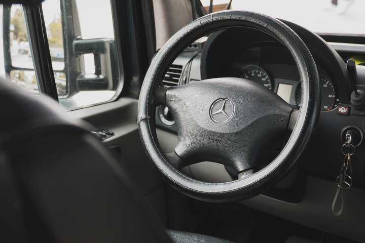 Close-up of a Mercedes-Benz steering wheel and dashboard inside a vehicle.
