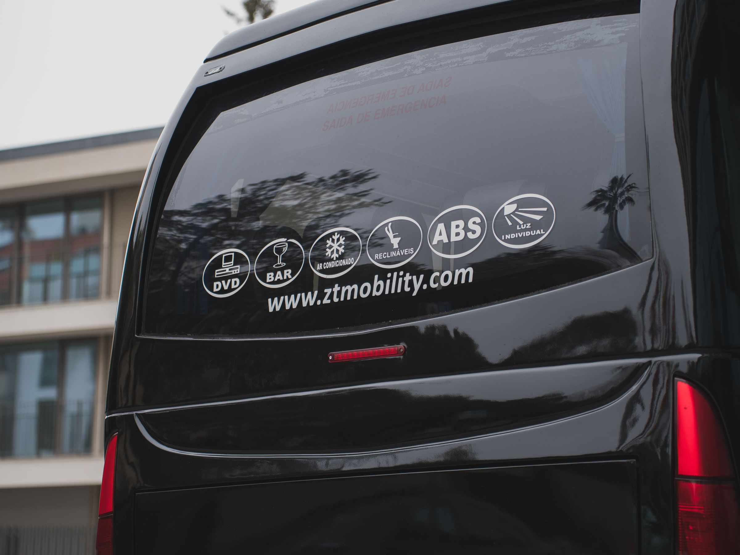Rear window of a black van with service icons and website URL.