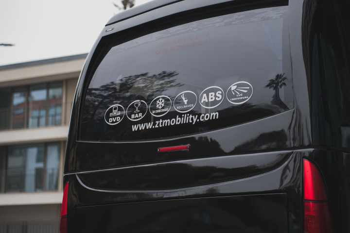 Rear window of a black van with service icons and website URL.