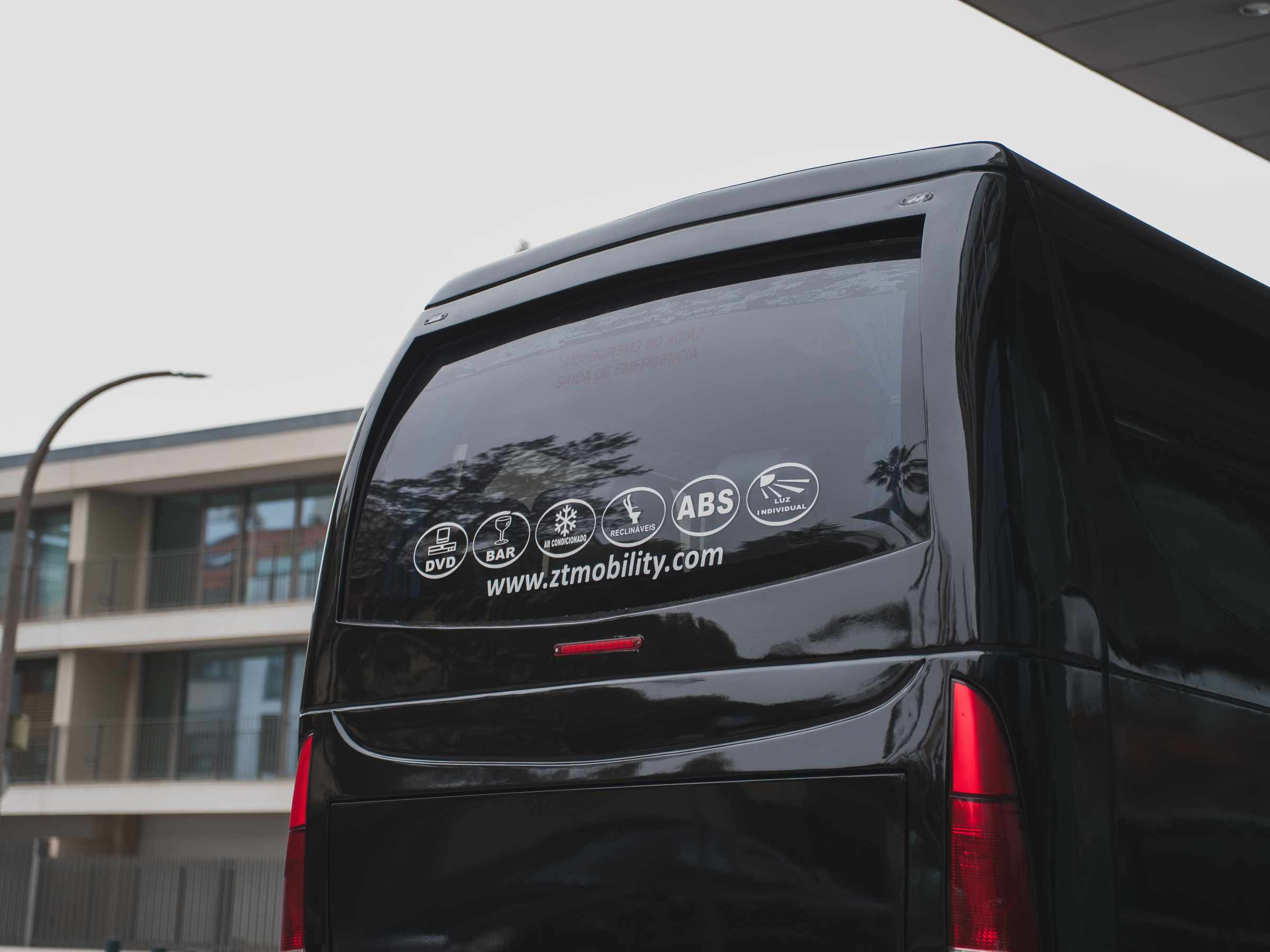 Back of a black van with decals and a website in an urban setting.