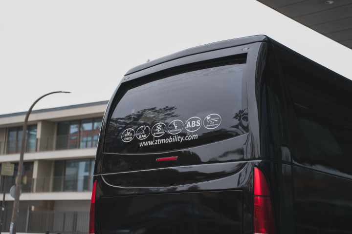 Back of a black van with decals and a website in an urban setting.