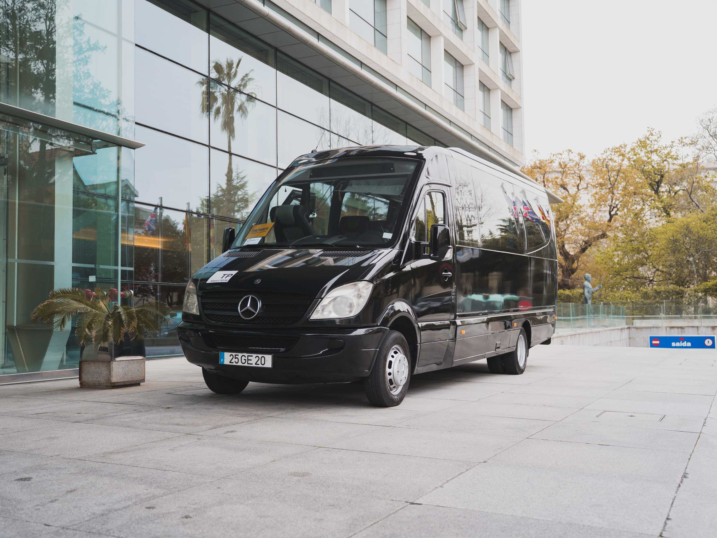 Black Mercedes van parked in front of a glass building.