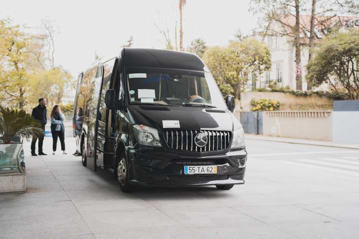 Black van parked on a street with people standing nearby.