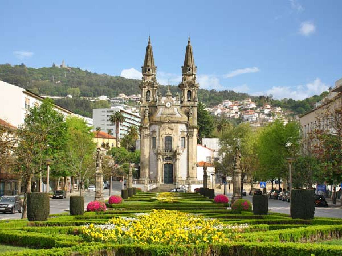 a church with a tall clock tower sitting in the grass