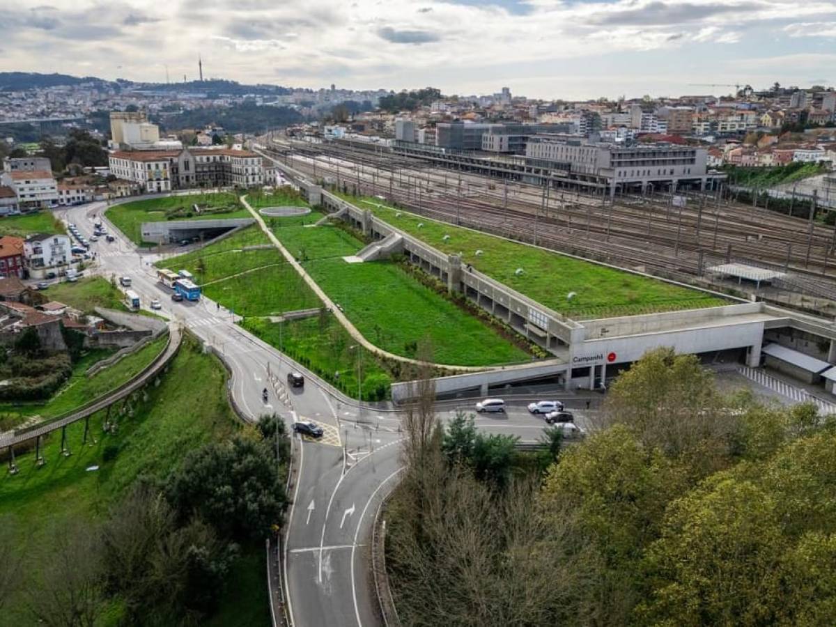 Aerial view of urban railway station with grass-covered roofs and surrounding roads.
